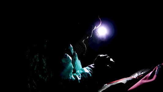 晚上在大自然中坐着手电筒的人影视素材在茂密的森林的漆黑中图片