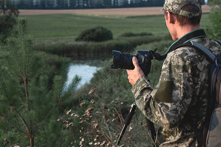 摄影师在池塘背景上用摄像头的手拿着照图片