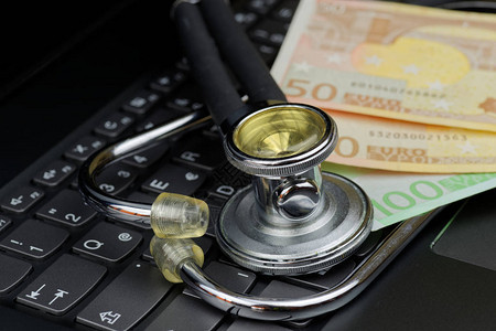黑色计算机键盘上的听诊器和欧元货币的图片