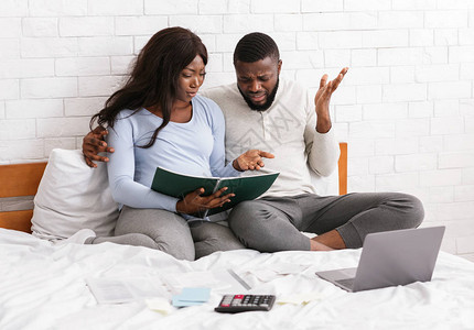 年轻的预期非洲夫妇讨论家庭预算问题图片