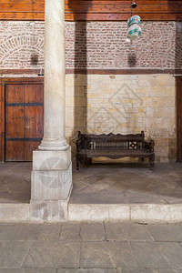 历史悠久的马穆鲁克时代Beshtak宫QasrBashtak主厅的石砖墙和陈旧的木沙发背景图片