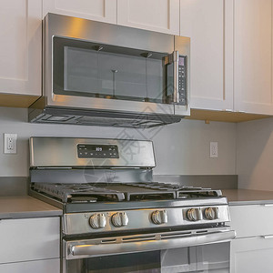 现代化厨房内的FrameSquare烹饪范围和壁挂式微波炉白色的木制橱柜建在厨房背景图片
