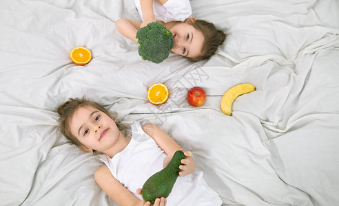 有两个可爱的小孩在轻薄的背景下玩水果和蔬菜图片