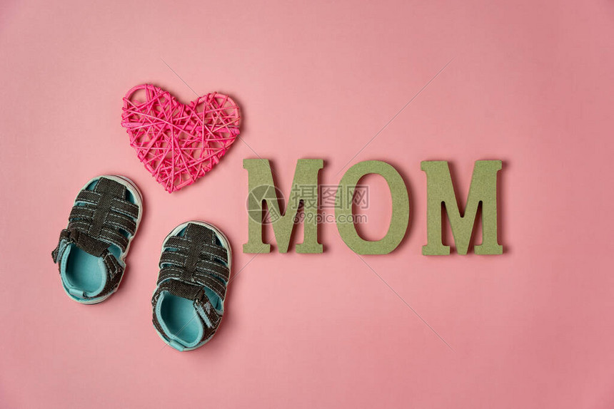 顶视图装饰的空中图像快乐的母亲节假期背景概念平躺婴儿鞋和妈在家办公桌上现代美丽的粉红色纸上的文字柔和的图片