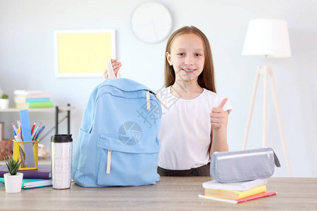 可爱开朗的女学生把文具放在背包里为上学做准备回到学校背景图片