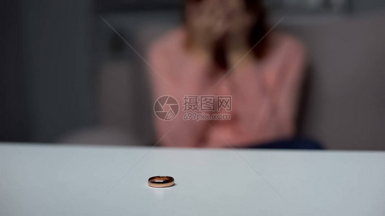 结婚戒指在桌上哭泣女人的背景夫图片