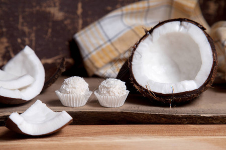 椰子和甜巧克力椰子松露椰子壳椰子片小块碎坚果和木制背景上的白巧克力椰子糖带壳的背景图片