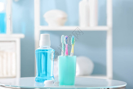 浴室桌上有牙线和漱口水的牙刷图片