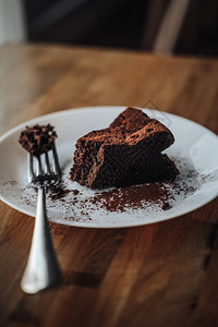 一片纯素巧克力布朗尼蛋糕放在木桌上无糖无小麦无奶无面粉甜点黑暗的心情食物照片健康饮食生活方式概图片