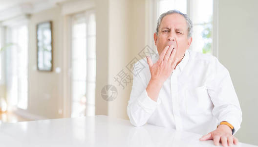 在家的英俊老人厌倦了打哈欠用手遮住嘴图片