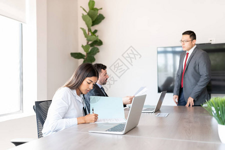 女商人坐在办公室会议室与男同事讨论时图片