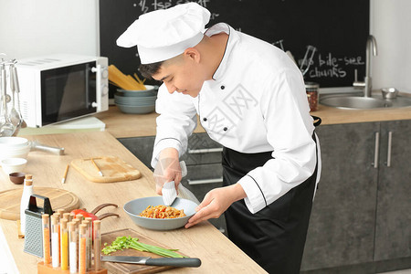 英俊的亚洲厨师在厨房做饭图片