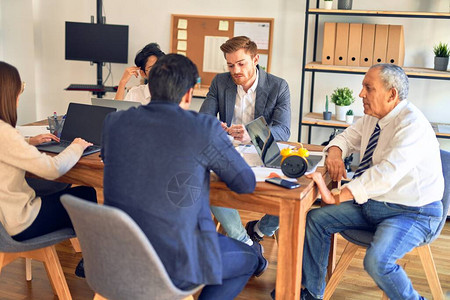 一群商业工作者一起工作坐在办公桌上使用笔记本电脑和图片