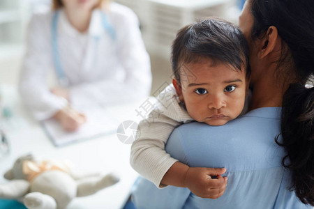 关于年轻母亲在医院看儿科医生时抱着小孩图片