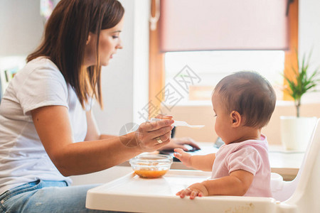 妈用勺子喂小女儿在网上搜索食谱图片