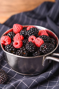 桌上放着美味的黑莓和覆盆子的锅图片