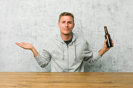 年轻人在餐桌上喝啤酒在问话的手势中怀疑图片