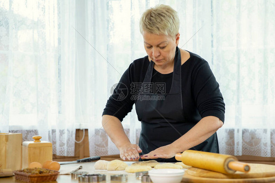 穿着黑色围裙的中年妇女在乡间别墅的厨房烹饪课上制作自制饼干和糕点揉面团家庭传统概念自制烘焙课概图片