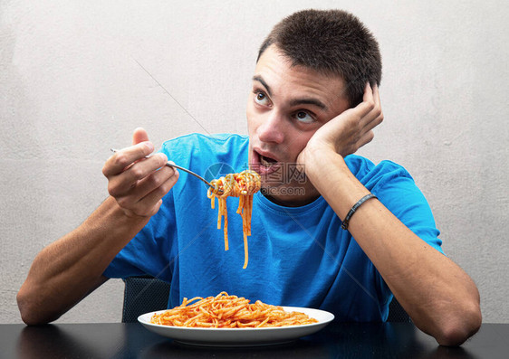 一个年轻男人吃意大利面图片