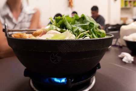 小火锅配蔬菜和肉在餐厅背景图片