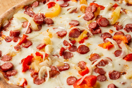 木制背景上的美味意大利披萨墨西哥辣椒热香肠洋葱西红柿和奶酪的热比萨饼的顶图片