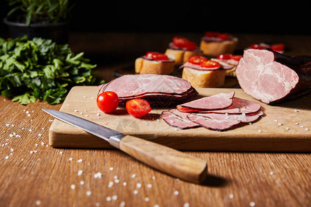 精选地聚焦美味的火腿切片樱桃西红柿和刀子图片