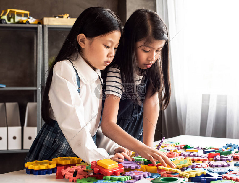 两个小女孩在家庭工作室一起玩塑胶游戏带着有兴趣的感觉露丝闪光效应周图片