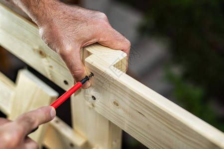 成年木匠工用螺丝刀拧螺丝以固定木栅栏的木板家务事自己图片