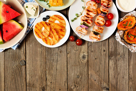 夏季BBQ或野餐选择烤肉水果和土豆在生锈木本底的视野之上图片