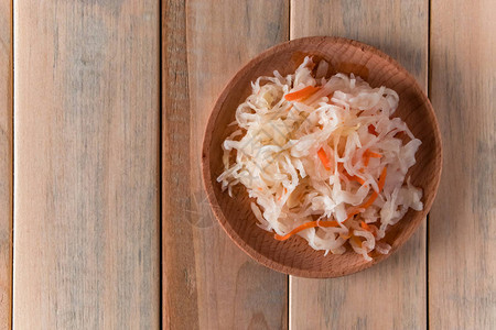 木板上的自制酸菜在浅色背景上加胡萝卜的发酵卷心菜生态食品图片
