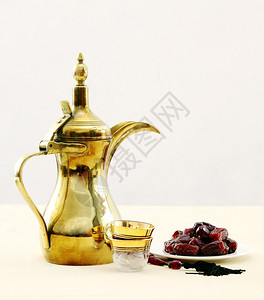 一个带玻璃咖啡杯的传统阿拉伯咖啡壶一盘枣子和一组念珠咖啡和红枣通常在禁食p背景图片