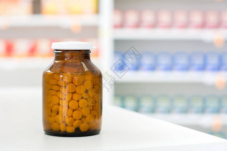 药房餐桌上透明琥珀药瓶中的小药丸图片