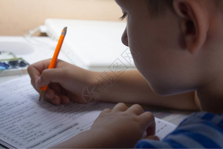 家庭教育男孩手用笔在传统的白色记事本纸上手写英语测试男孩给朋友写了一封信放学图片