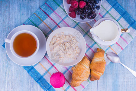 健康早餐带羊角面包的茶和带浆果的燕图片