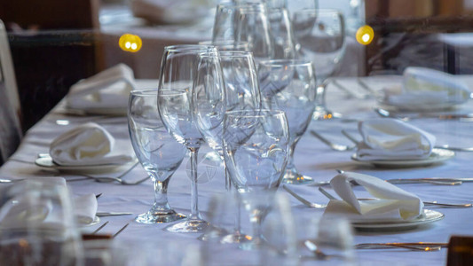 Wine眼镜和餐具安排在社会聚的桌子上图片