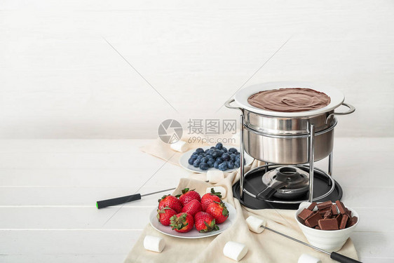 桌上放着融化的巧克力和浆果的火锅图片