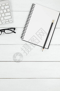 白色木质背景上带有开放式空白笔记本铅笔眼镜和白色键盘的最小办公图片