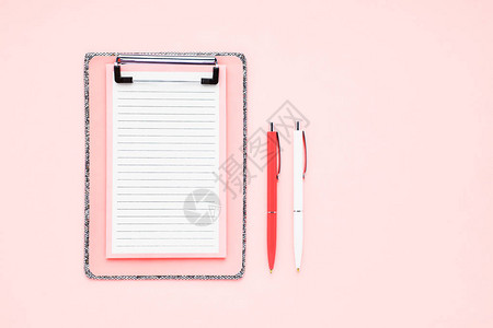 粉红色背景上的空白剪贴板模型和圆珠笔图片