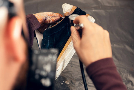 手工艺人画在一双鞋上油漆和修复皮图片