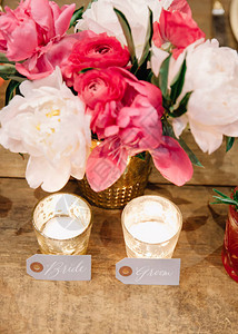 放在水银玻璃蜡烛以及白花和粉红花边旁的婚礼桌上的图片