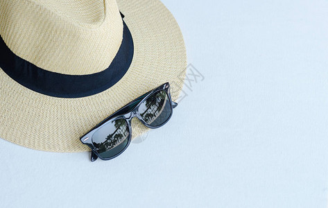 白色桌子上有黑丝带和太阳墨镜的沙滩帽图片