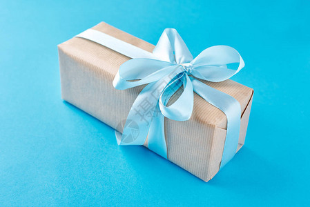 用蓝色背景上的蓝丝带在工艺纸中关闭礼品盒图片