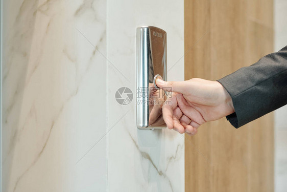 商人在酒店或办公中心内站在门口等电梯时按图片