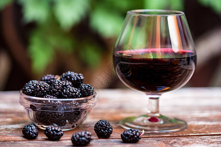 露天桌外的碗和杯子上木莓葡萄酒中深熟成的芒果夏季食物概念图片