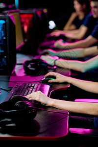游戏笔记本坐在电脑监视器前的办公桌旁和玩网络游戏的当代电子体育俱乐部青年俱乐背景