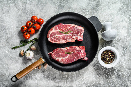 煎锅中的生猪肉牛排盘剥的农场肉灰色背景顶视背景图片