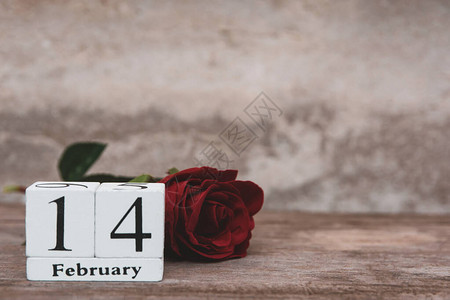 14月14日的情人节Wooden白块日历红玫瑰和红心在木桌背景上图片