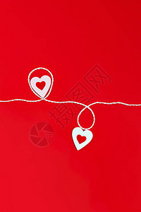 在红色背景上用白色和红色的心和一根白色的绳子图片