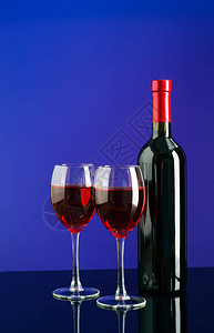 两杯红葡萄酒和一瓶红酒亮蓝色背图片