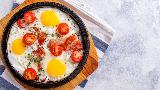 用鸡蛋培根和西红柿煎锅早餐概念顶视图片